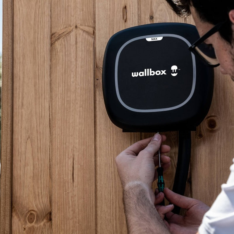 Installation einer schwarzen Pulsar Max Wallbox an einer Holzwand.